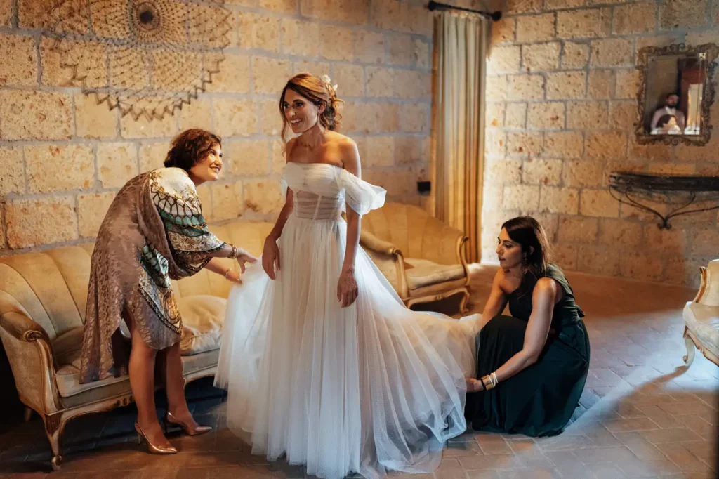 The bride is getting ready in an abbey room with two of her friends