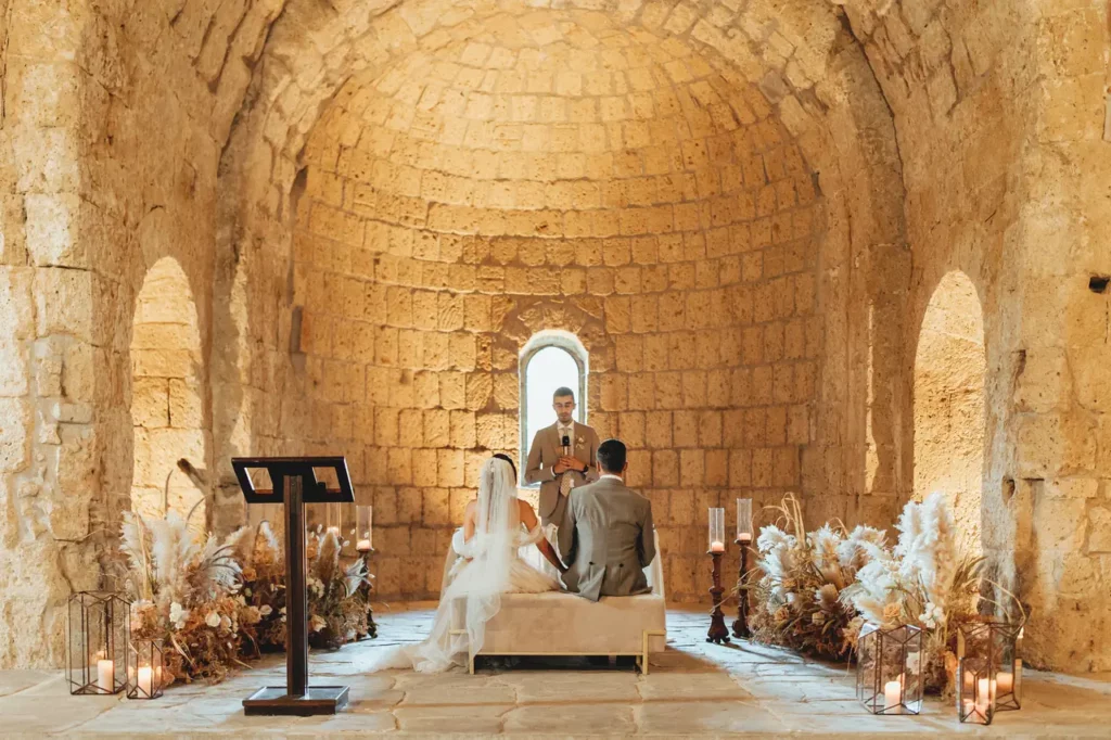 The bride and groom during the ceremony sitting on the pew
