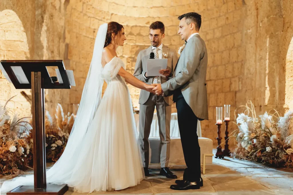 Gli sposi si tengono per mano durante la cerimonia matrimoniale all'abbazia di san giusto, tuscania