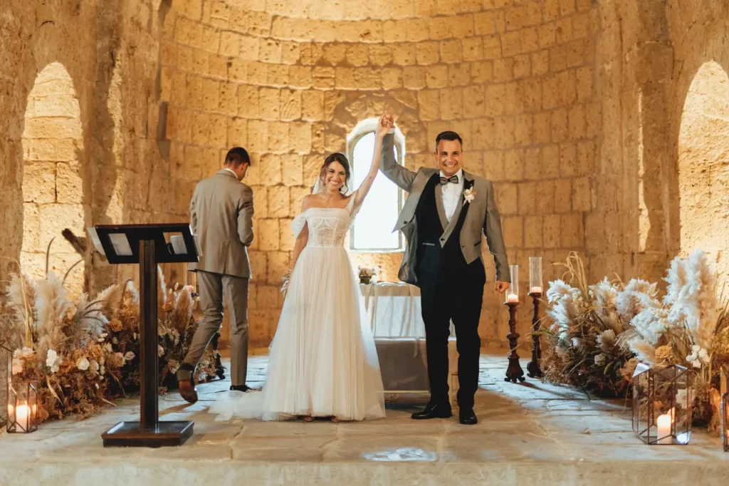 Happy bride and groom raise their arms at the end of the ceremony inside the church