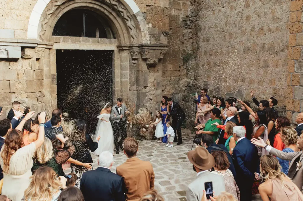 Rice throwing as the bride and groom exit the church of san giusto abbey, tuscania