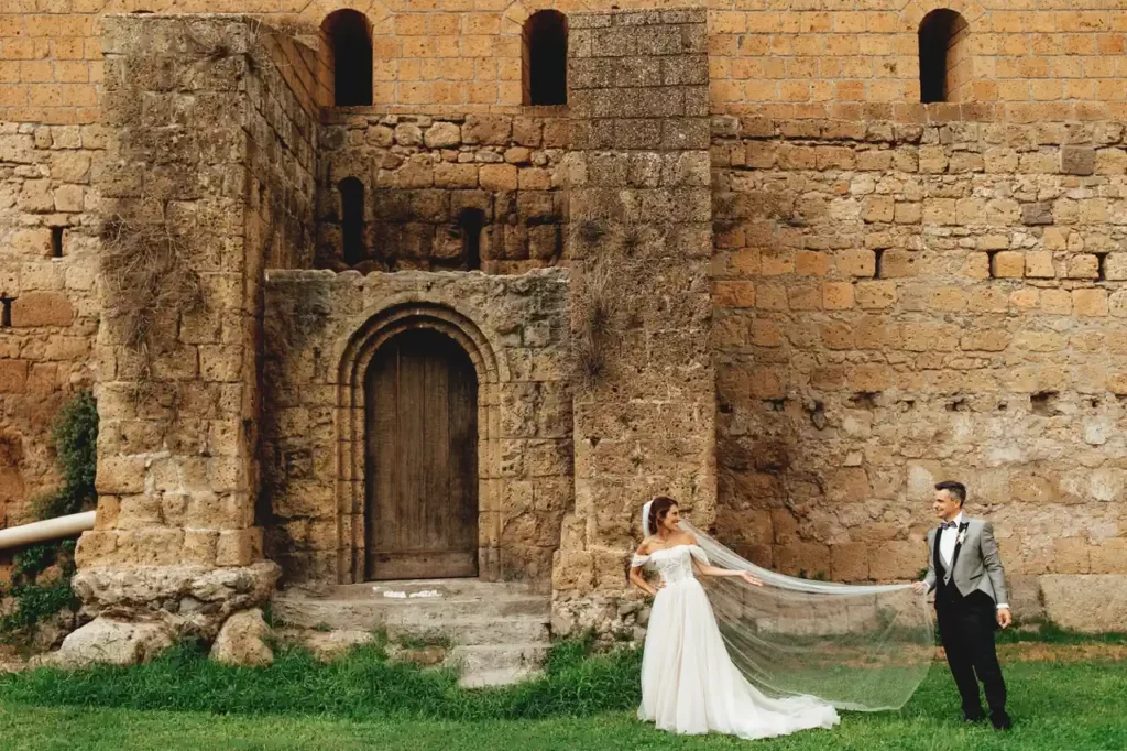 Newlyweds at San Giusto Abbey, Tuscania, posing romantically in front of its walls.