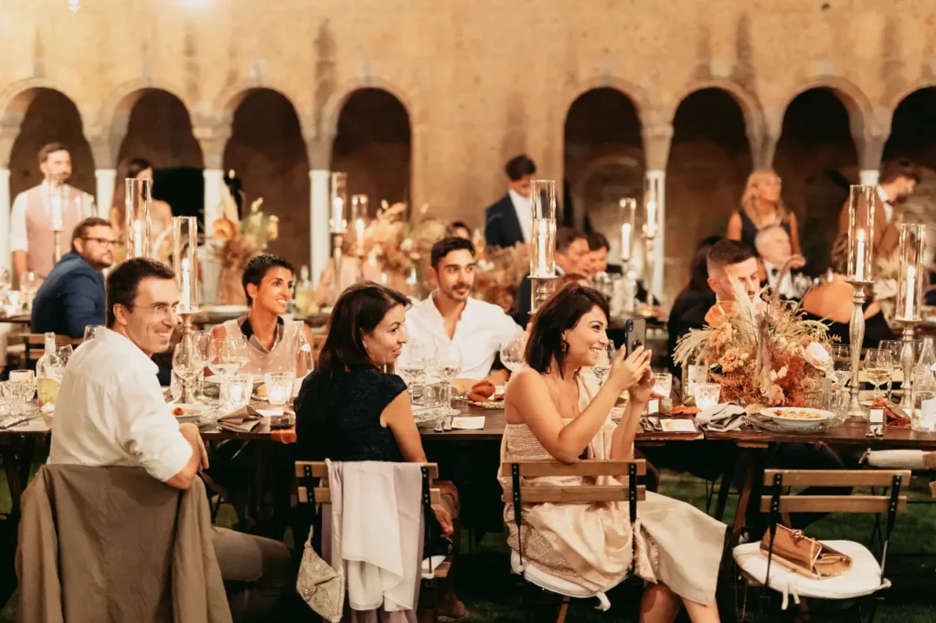 Invitati al matrimonio seduti attorno ai tavoli durante il ricevimento di nozze.