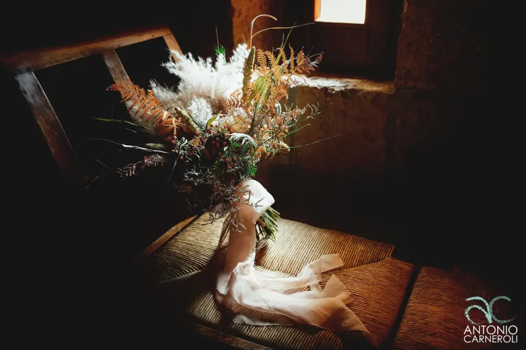The bride's bouquet is placed on a chair, against the light, in a semi-darkened room.