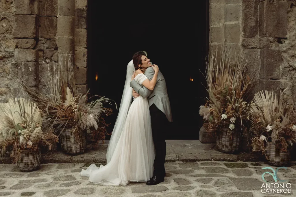 The bride and groom embrace in front of the church of san giusto abbey