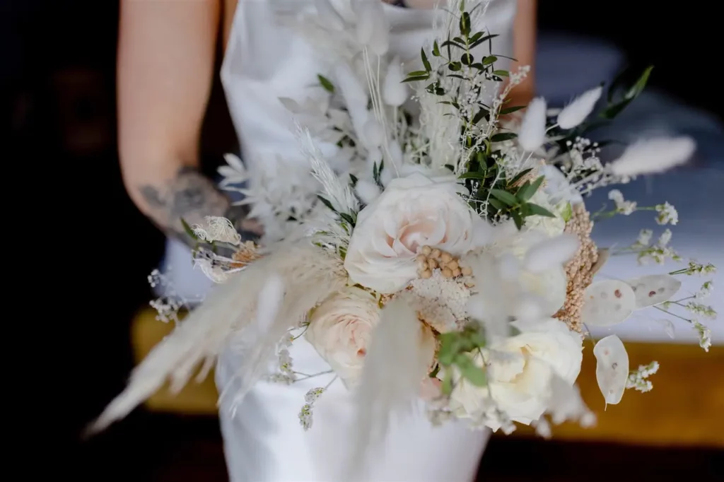 A bride holding a delicate white and green floral bouquet.