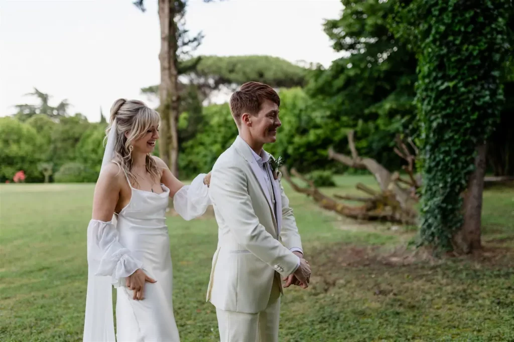 A bride approaches the groom, both dressed in wedding attire