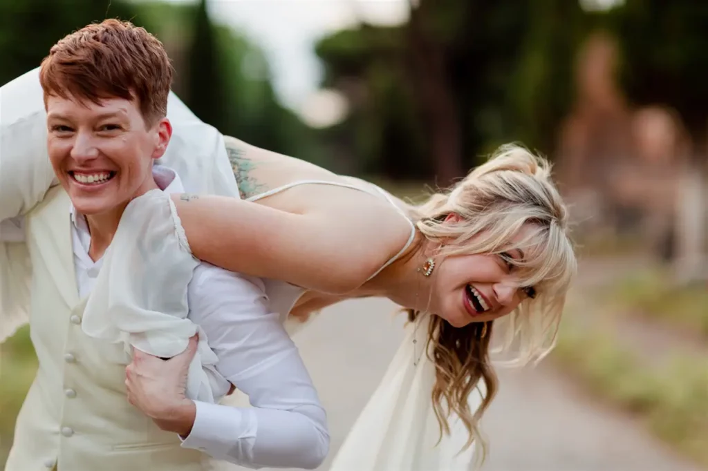 The amused bride is carried on the shoulders of the groom