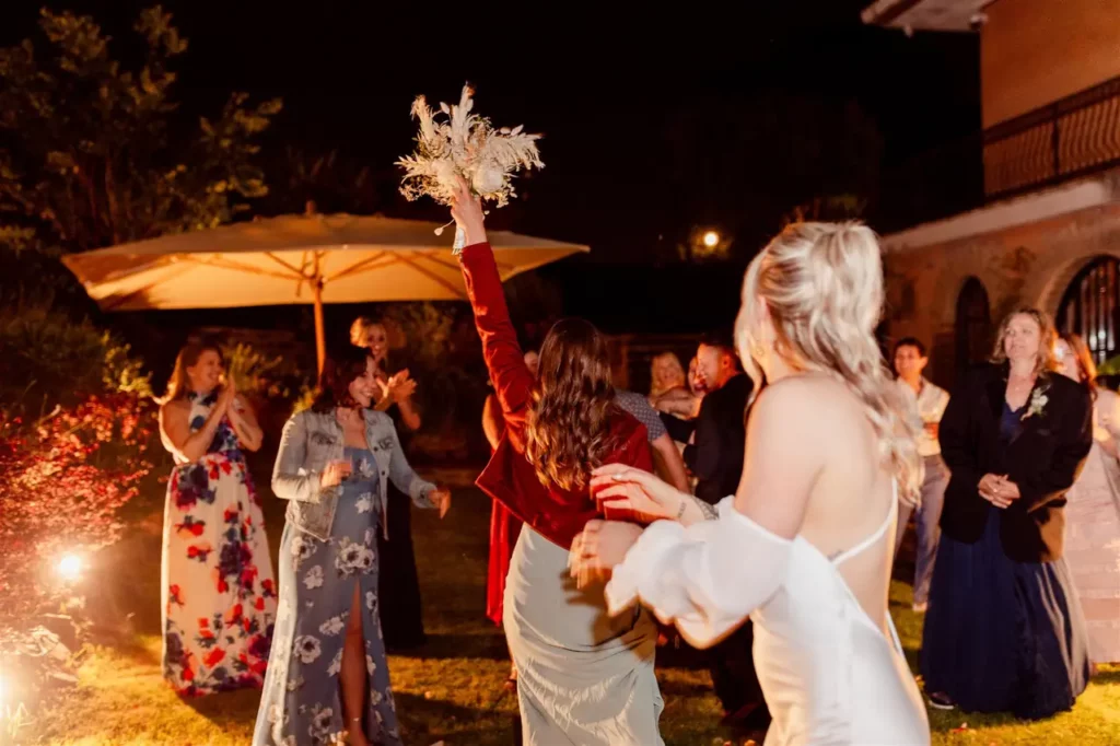 A guest picks up the bouquet thrown by the bride