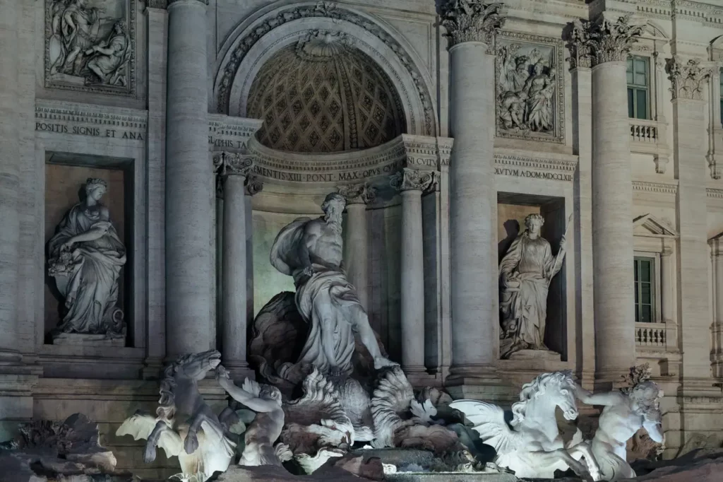 Vista notturna della Fontana di Trevi a Roma con le sue sculture e gli elementi architettonici illuminati.