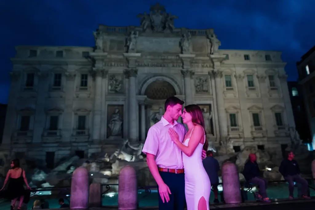 A couple embracing in front of the Trevi Fountain at dawn.