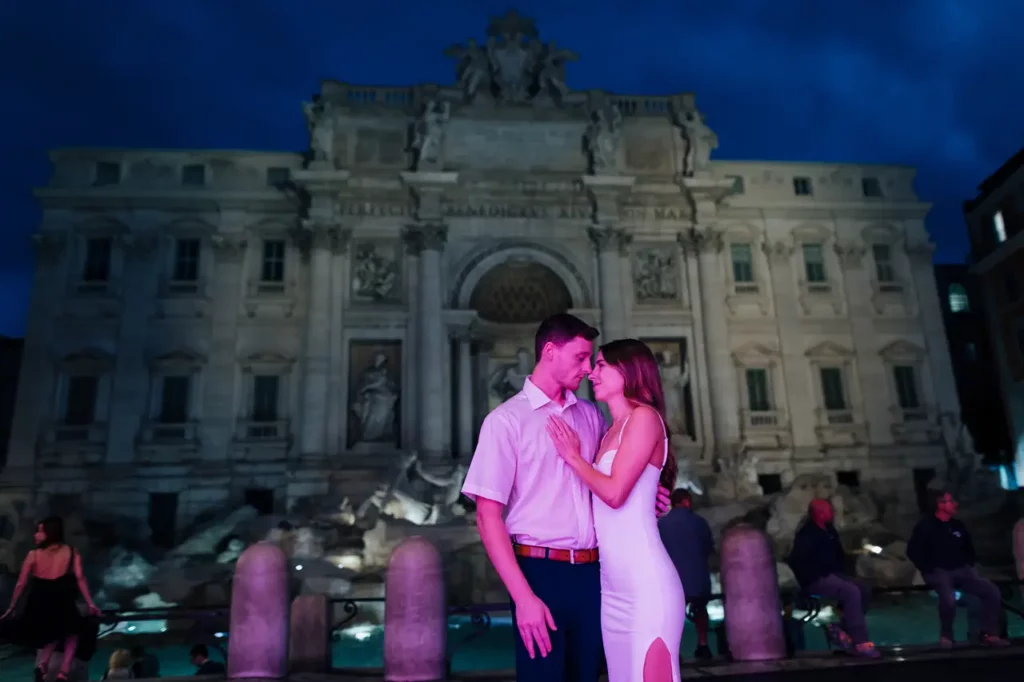 A couple embracing in front of the trevi fountain at dawn.