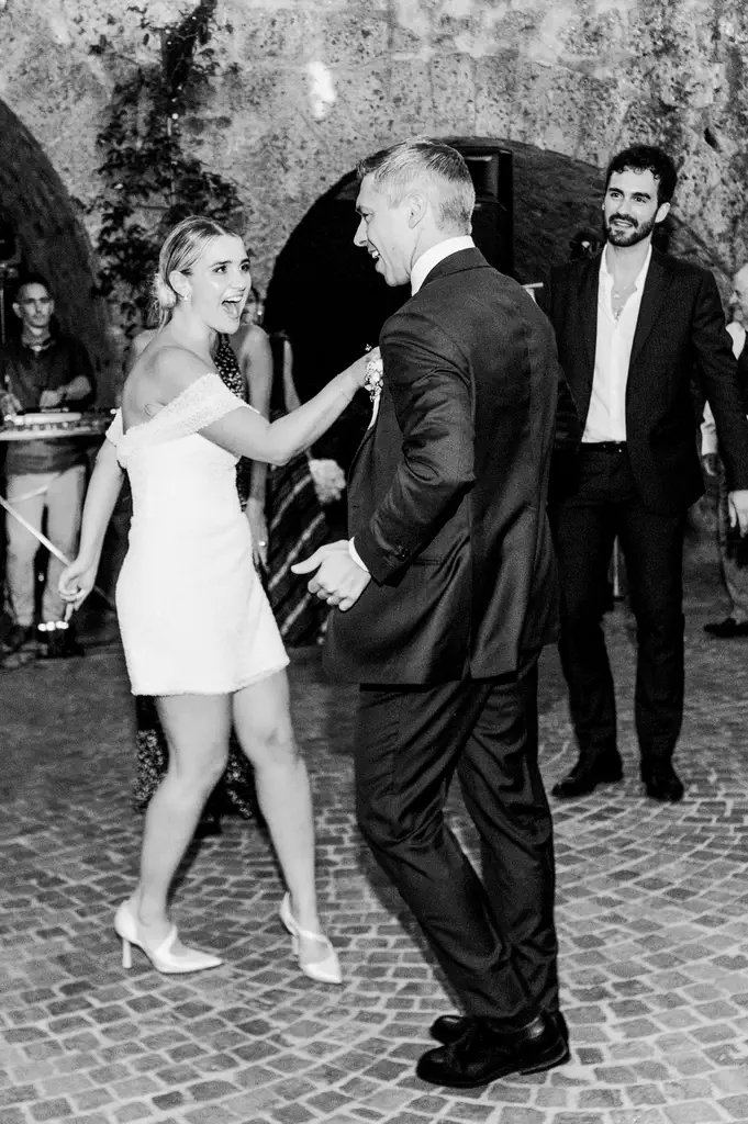 Federico and chiara wedding in civita castellana A formally dressed man and woman dance together at an event while others watch in the background.