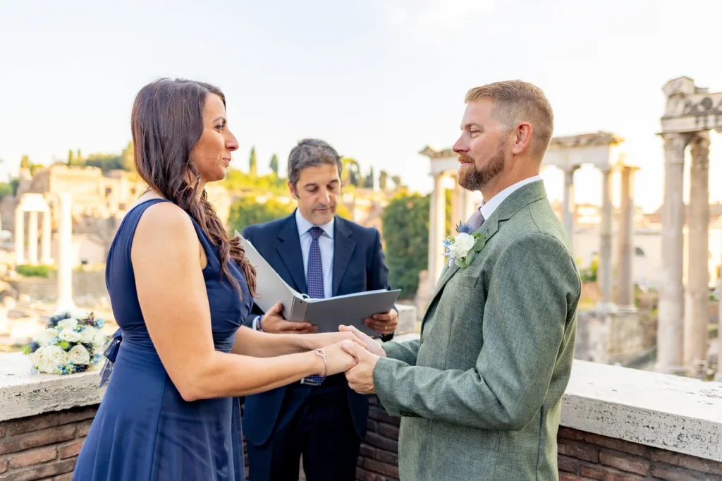 A couple exchanges wedding vows in a celebrant-led outdoor ceremony against the backdrop of ancient ruins.