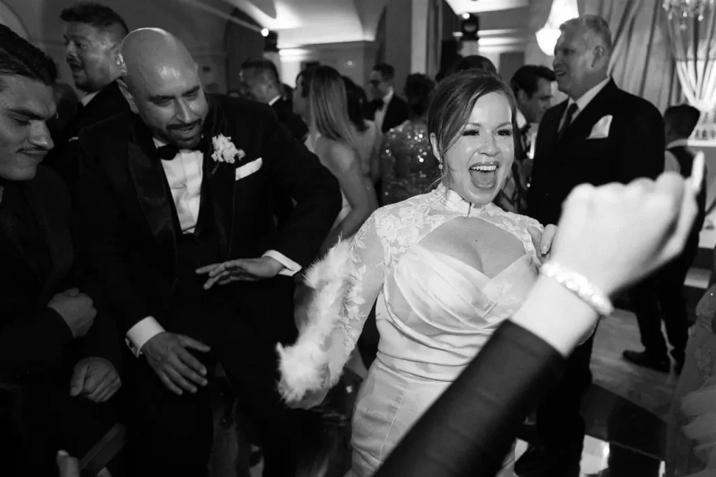 A group of people in formal dress dances energetically in a lively indoor setting.